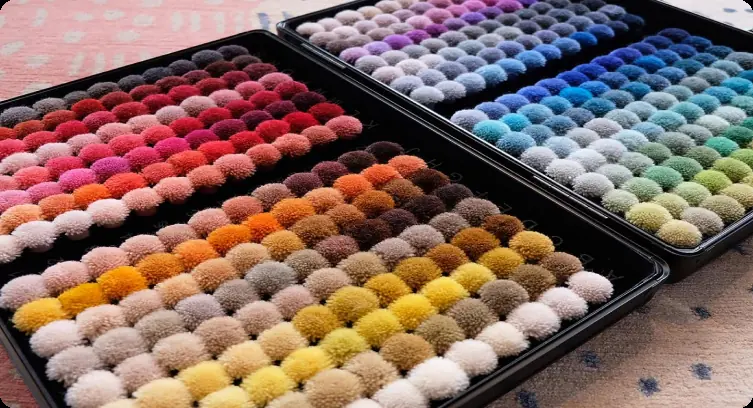 Open trays of wool colour poms, the shades a custom carpet is dyed to